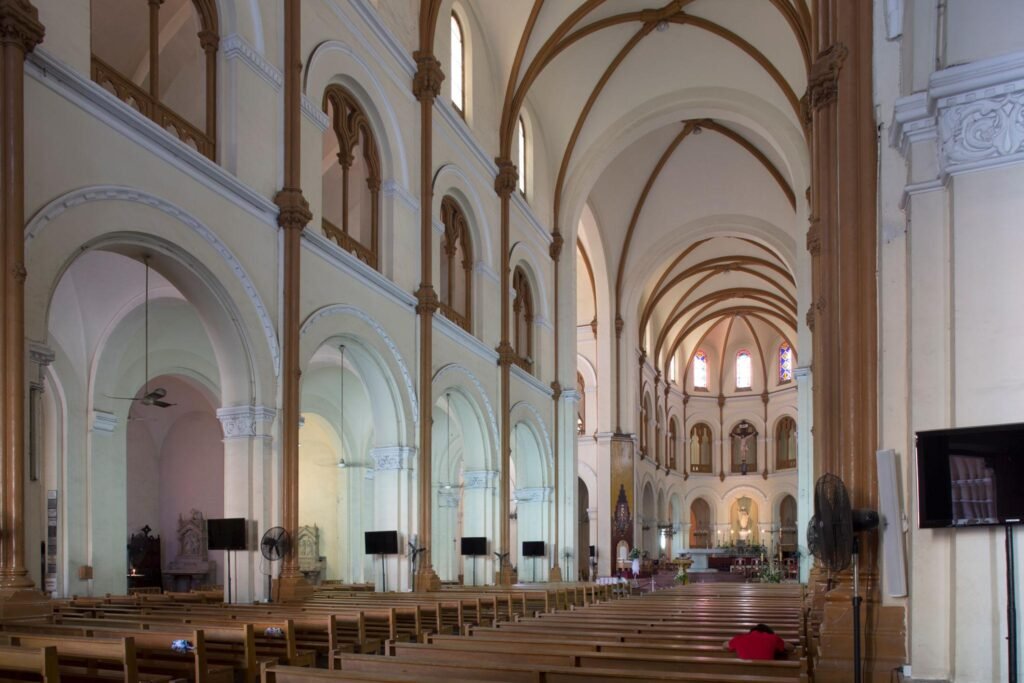 Inside, natural light becomes part of the experience. Sunlight enters through stained glass windows and gradually moves across wooden furnishings and quiet prayer spaces throughout the day
