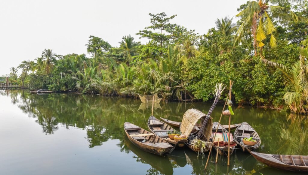 A traditional wooden boat traveling through a peaceful Mekong Delta canal.